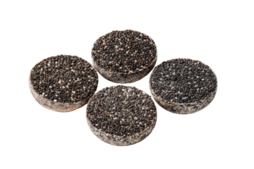 Four dark, round, speckled food items, arranged in a loose, slightly overlapping pattern against a black background. The specks are small and uniformly distributed across each disk