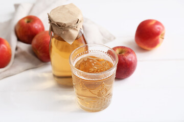 Fresh fruits with bottle and glass of apple cider on white wooden background