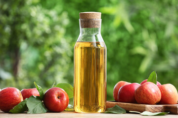 Fresh fruits with bottle of apple cider on beige table outdoors