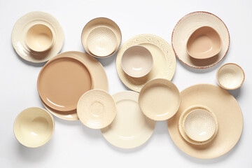 Set of beige plates and bowls on white background