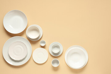 Set of white plates and bowls on beige background