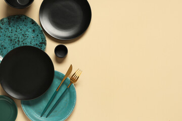 Set of plates and cutlery on beige background