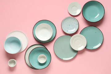 Set of clean plates and bowls on pink background