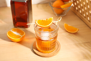 Glass of tasty Old Fashioned Cocktail with oranges on wooden table