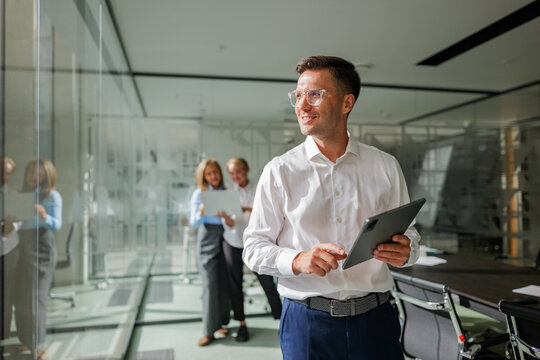 Business meeting in a modern office with a young professional presenting ideas using a tablet, while colleagues observe and engage with enthusiasm