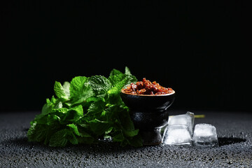 Hookah bowl of tobacco with ice cubes and mint leaves on black background