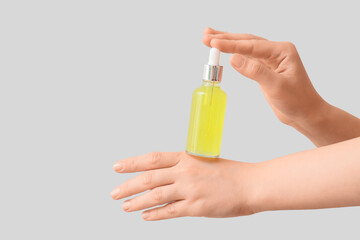Female hands with bottle of essential oil on white background