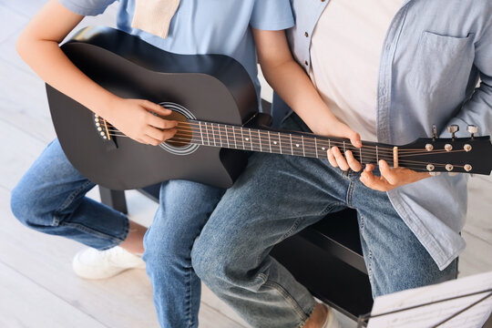 Cute boy learning guitar with private music teacher in room - Powered by Adobe