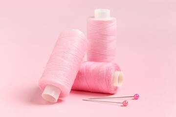 Spools of thread with ball pins on pink background