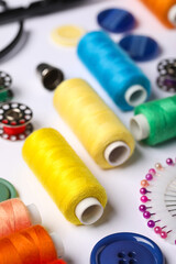 Composition with different thread spools and accessories on white background, closeup