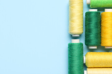 Different sewing thread spool on blue background, closeup