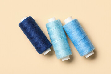 Set of thread spools on beige background, closeup