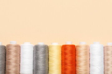 Set of different thread spools on beige background, closeup