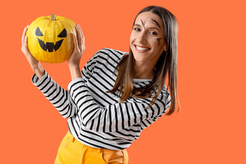 Beautiful young happy woman with Halloween pumpkin on orange background