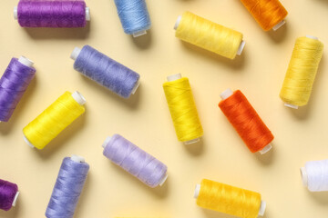 Many colorful thread spools on beige background
