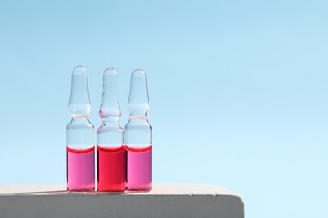 Glass ampoules on podium against light blue background