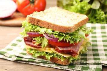 Delicious sandwich with ham, cheese and vegetables on wooden table, closeup