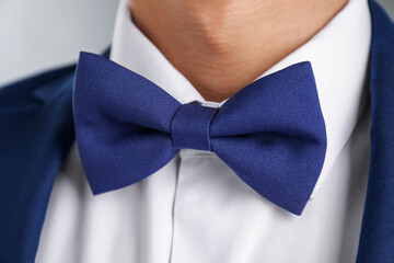 Man in suit with stylish bow tie on grey background, closeup