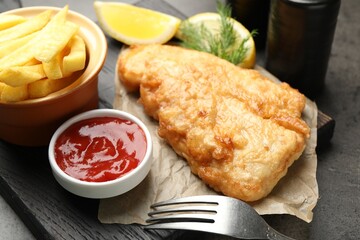 British Traditional Fish and chips served with sauce on grey table, closeup