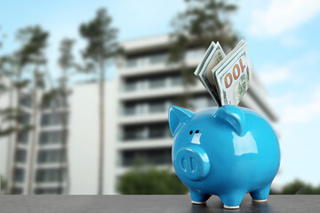 Obraz premium Piggy bank with dollars against condominium. Saving money to buy apartment