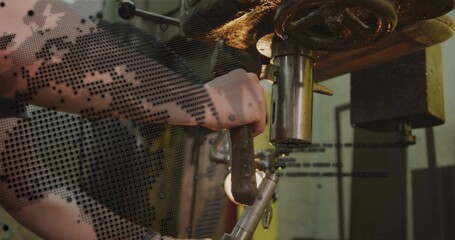 Operating technician gripping lever at workshop, with drill press, metal workpiece and code overlay