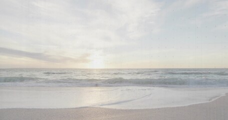 Rolling ocean waves approaching smooth sandy shoreline at sunset, under scattered pastel clouds