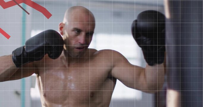 Punching shirtless bald man delivering punch on heavy punching bag in gym, with black boxing gloves