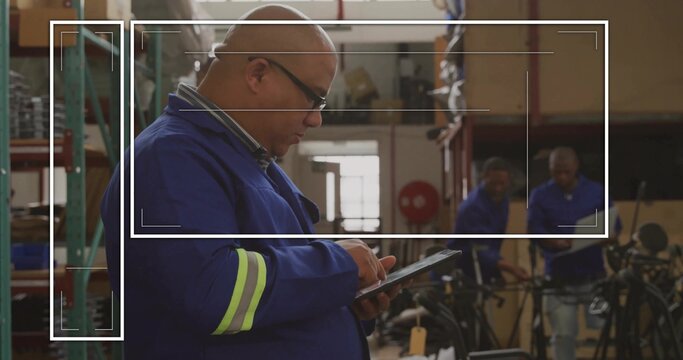 Examining technician in blue uniform using tablet in bike repair shop, with bike frames, copy space