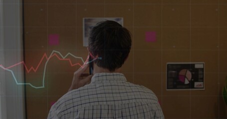 Monitoring man studying pink notes and pie chart overlays on office corkboard, holding smartphone