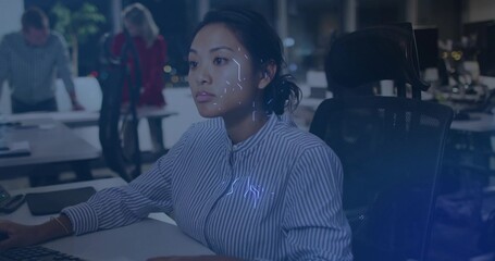 Working adult Asian woman typing on keyboard at office at night, with holographic facial overlay