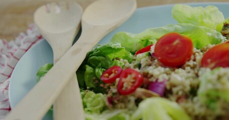 Displaying quinoa salad on pale blue plate on wood table, checkered cloth, crossed wooden spoons