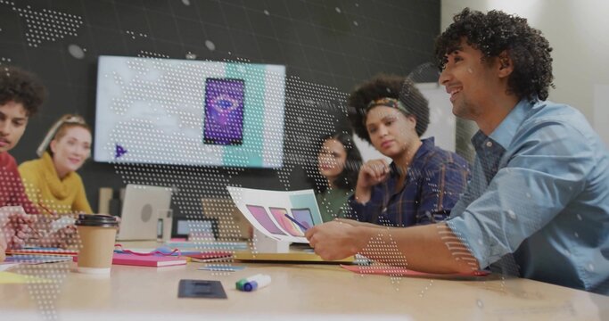 Four colleagues reviewing mock-ups and color swatches in conference room, with wall-mounted monitor - Powered by Adobe