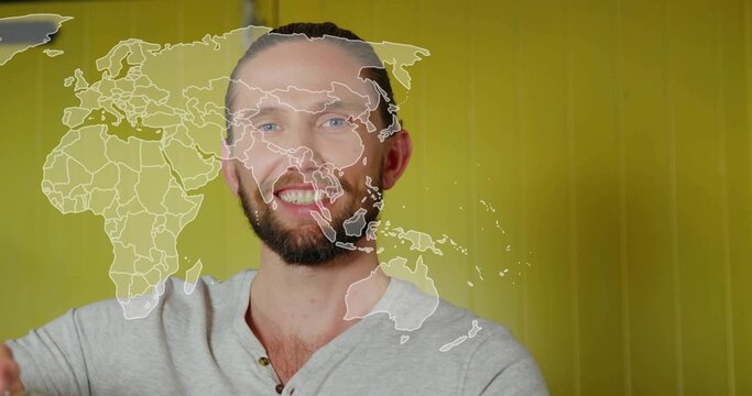 Smiling male presenter in grey henley shirt sharing global trends in studio, with world map overlay - Powered by Adobe