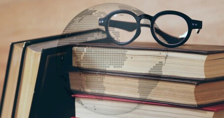 Resting black eyeglasses on hardcover book stack on desk, with digital globe overlay