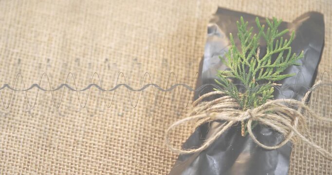 Thin coil spring appearing at left edge extending sideways across burlap highlighting wrapped gift