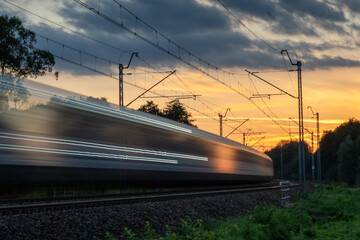 a speeding train blurred in the light of the setting sun
