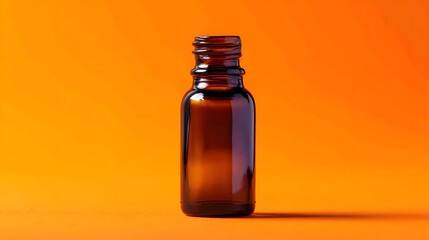 Amber glass bottle with threaded neck rests on a vibrant orange surface.
