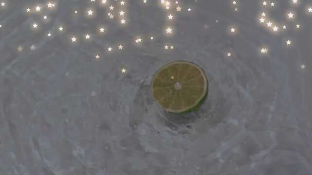 Upon dropping lime half-slice creating ripples while bobbing and sparkles drifting decorating scene
