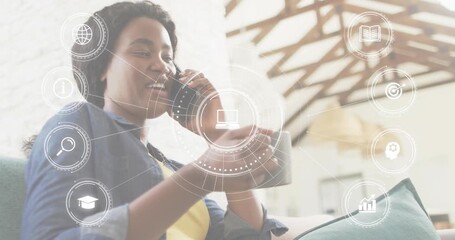Businesswoman lifting smartphone for virtual meeting while holographic icons orbiting around hand - Powered by Adobe