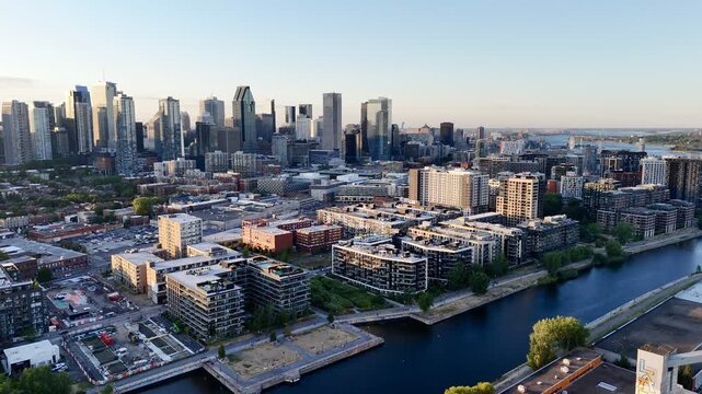 Aerial view of modern waterfront district with high-rise buildings and riverside paths, Montreal twilight skyline. g.