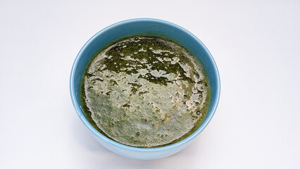 Green grass jelly or cincau hijau in blue bowl isolated on white background. Top view. Flat lay