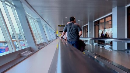 Modern Airport Terminal. Tourists on moving roads, illuminated by natural light from large windows. The sign above the head to direct the passenger. Tangerang, Indonesia, June 11, 2025