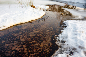 A film of petroleum products and oils floating on the surface of a river in the winter,...