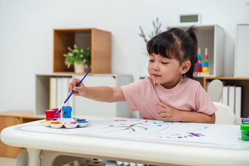 happy toddler girl painting watercolor in paper at home