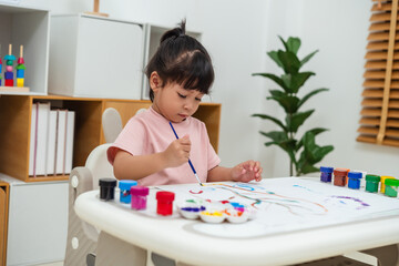 happy toddler girl painting watercolor in paper at home