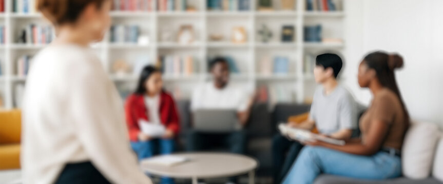 DSLR photo of a diverse business team engaged in a collaborative meeting indoors, warm daylight illuminating faces and laptops around a sleek modern workspace.