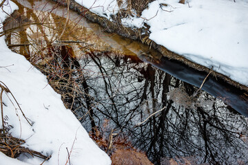 A film of oil and grease on the surface of a frozen stream, contaminating the natural surroundings...