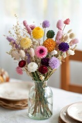a bouquet of dried flowers, including strawflowers and gerbera daisies, is arranged in an elegant display on the table.