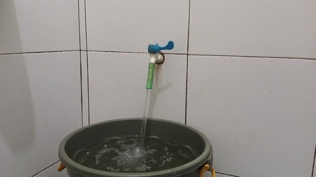 Scene women hand Turn on kran to fill bucket of water in the bathup