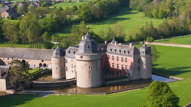 castle lavaux sainte anne or ch&acirc;teau de old building green fields water body gardens trees town background hills to left around right close pans drone panning 